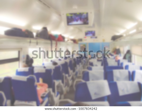 Interior of a passenger train. Seats,\
monitors, things of passengers on the shelves. Without people.\
Blurred image, can be used as a\
background.