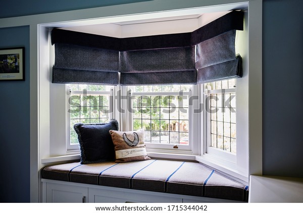 Interior photography of a bay window with\
banquette seat and cushions in a Victorian\
home
