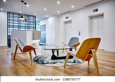 Interior Photography Of Commercial Fit Out Of Corporate Office In Minimalist Modern Design In Whites And Greys With Reception Desk, Waiting Area, Pendant Lighting And Lift Lobby In Background