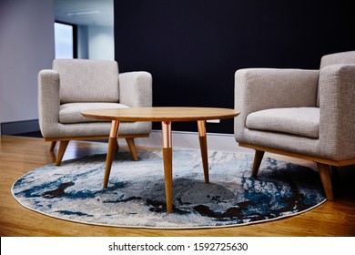 Interior Photography Of Commercial Fit Out Of Reception Waiting Area With Modern Grey Arm Chairs, Coffee Table, Rug And Dark Feature Wall And Office In Background