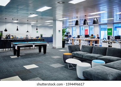 Interior Photography Of Commercial Fit Out Of Modern Office Break Out Area In Open Plan Office With Pendant Lighting, Sofas And Stools, Pool Table, Kitchen, Open Plan Office And Staff In Background