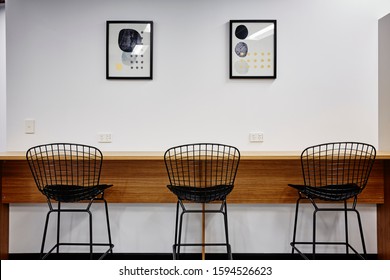 Interior Photography Of Commercial Fit Out Of Modern Office Break Out Area With Tall Table Against Wall With Black Mesh Metal Bar Stools And Framed Art On Wall