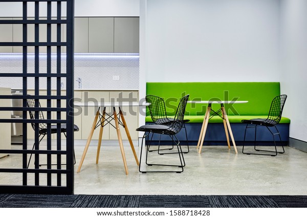 Interior photography of commercial fit out of\
corporate break out lunch area in modern minimalist design with\
graphic room divider with tables and\
chairs