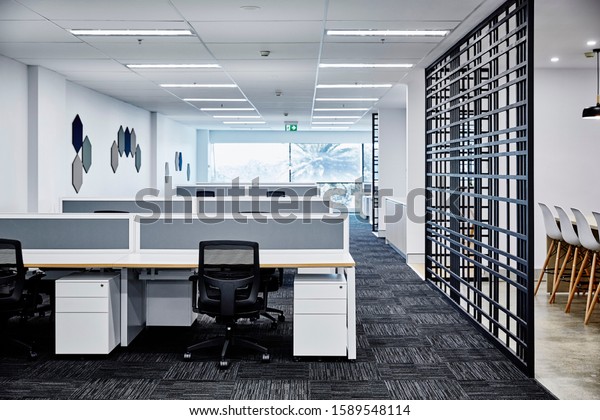 Interior photography of\
commercial fit out of corporate office in minimalist modern design\
in whites and greys, office work stations with breakout area to the\
right