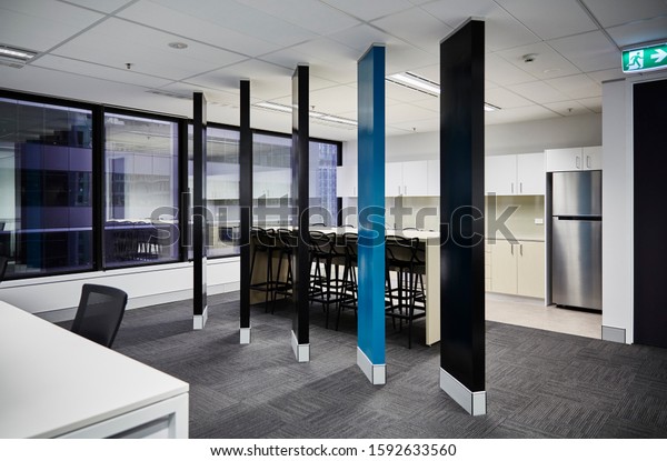 Interior photography of commercial fit\
out of office break out area with kitchen, modern graphic style\
room divider in black and teal and black\
furniture