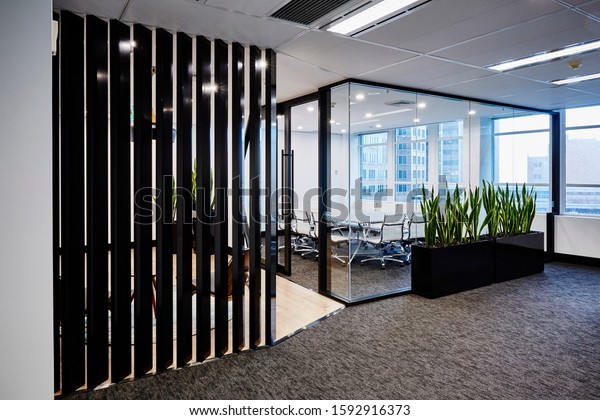 Interior photography of commercial fit out of room\
divider, board meeting room with modern white table and chairs with\
city view in background, sansevieria planter boxes, view from\
outside looking in