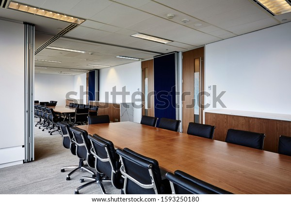 Interior photography of commercial fit out of\
board meeting rooms with room dividing concertina wall moved back\
to display both rooms containing long timber tables and black\
leather chairs