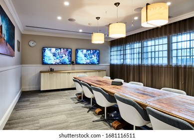 Interior Photography Of A Contemporary Board Room With A Large Rustic Timber Meeting Table, Swivel Chairs, Pendant Lighting & Timber Cabinetry, Wall Mounted Screens And Curtain Sheers