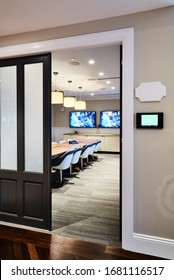 Interior Photography Of A Contemporary Board Room With A Large Rustic Timber Meeting Table, Swivel Chairs, Pendant Lighting & Timber Cabinetry, Wall Mounted Screen, Shot Through The Entrance Door Way