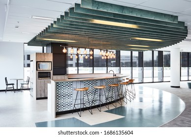 Interior Photography Of A Contemporary Design Corporate Office Break Out Area, A Kitchen With Pendant Lighting, Breakfast Bar & Stools And A Large Bank Of Windows