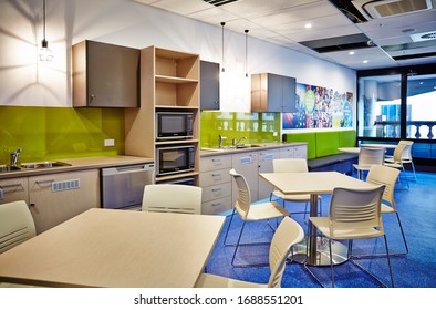 Interior Photography Of A Contemporary Design Corporate Office Break Out Area, A Kitchen Area With Tables And Chairs And A Blue Linoleum Floor