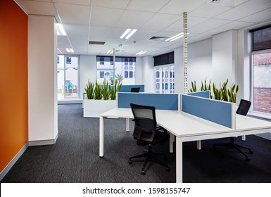 Interior Photography Of A Corporate Fit Out Open Plan Office Area With Desks, Filing Cabinets, Black Chairs, An Orange Feature Wall, Sansevieria Planter Boxes And A City View In The Background