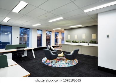 Interior Photography Of A Corporate Fit Out Open Plan Office Reception Meeting Area With Arm Chairs, Colourful Rug, Coffee Table And Open Plan Office And Breakout Area In Background