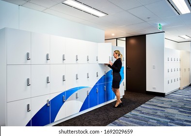 Interior photography of a corporate office staff locker area with a female employee opening her locker