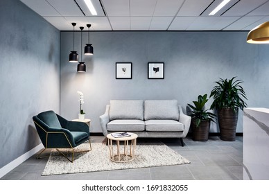 Interior photography of a corporate reception waiting area in grey tones with a marble stone front desk, lounge, pendant lighting and concrete tile flooring