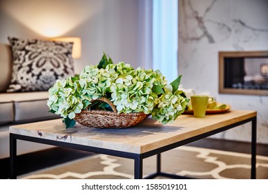 Interior Photography Detail Of Hamptons Style Lounge Room With Coffee Table Styled With Hydrangea Flowers With Sofa, Cushion, Marble Fireplace And Rug In Background