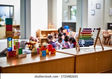 Interior photography detail of toys and educational equipment in a childcare center with preschoolers out of focus in the background
