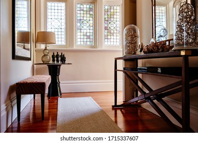 Interior Photography Of The Entrance Of A Renovated Victorian Mansion With Stained Glass Windows, Hall Stand With Decorative Objects, Framed Art And Timber Floor Boards