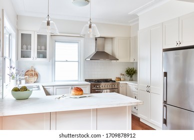 Interior Photography Of A Fresh White Hamptons Style Kitchen With Marble Bench Top, A Large Stainless Steel Stove/oven And Pendant Lighting