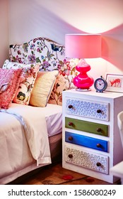 Interior Photography Of Girl Child's Bedroom With Bed, Painted Side Table With Lamp, Upholstered Bed Head, Hot Pink Details And Clock