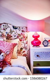 Interior Photography Of Girl Child's Bedroom With Bed, Painted Side Table With Lamp, Upholstered Bed Head, Toy Rabbit, Hot Pink Details And Clock