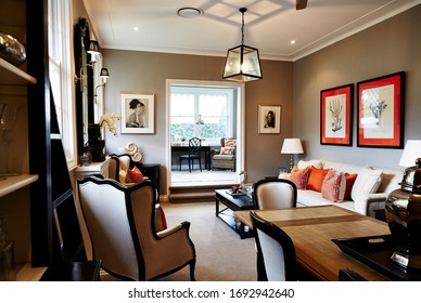 Interior Photography Of A Hamptons Style Formal Lounge Room With Wing Back Chairs, A Fireplace, Dining Room And A Sitting Room In The Background With Writing Desk And Arm Chairs