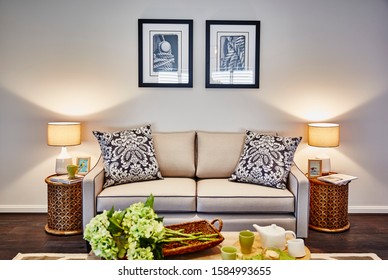 Interior Photography Of Hamptons Style Lounge Room Front On Angle With Cream Sofa, Framed Prints, Side Lamp And Table, Coffee Table And Rug