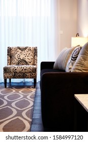 Interior Photography Of Hamptons Style Lounge Room With Dark Fabric Sofa, Scatter Cushions, Rug And Printed Upholstery Armchair