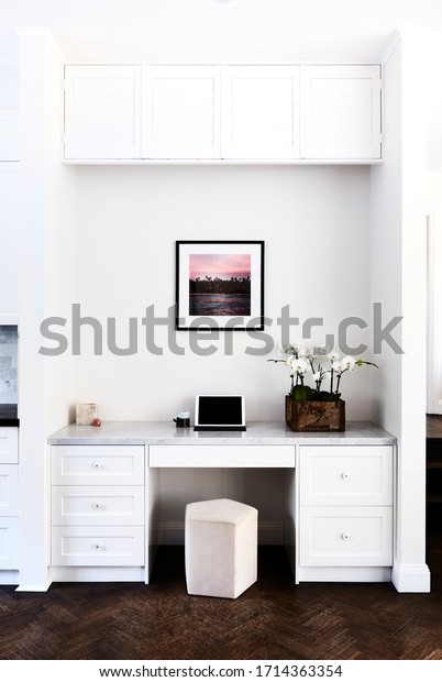 Interior photography of a home study media nook in\
a modern Hamptons style home with framed art, iPad, coffee mug and\
a potted phalaenopsis\
orchid