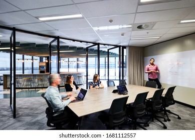 Interior Photography Of A Large Modern Board Room With Folding Glass Doors And A Break Out Area In The Background, Staff Holding A Meeting