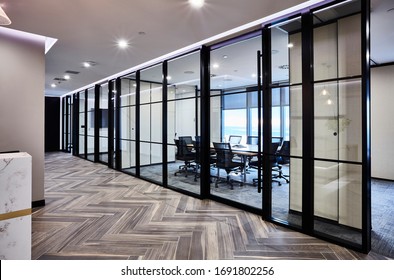 Interior photography of a large modern corporate board room in neutral tones with a timber meeting table, black chairs and glass walls and moveable walls
