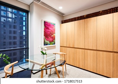 Interior Photography Of A Meeting Table In The Corner Of A Private Executive Office With City Views, Framed Art On The Wall And Storage Cabinets