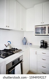 Interior Photography Of A Modern White Kitchen With Marble Bench Top, Stainless Steel Appliances, Kettle And Decorative Items