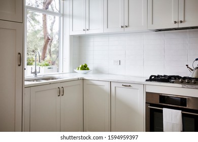 Interior Photography Of A Modern White Kitchen With Marble Bench Top, Stainless Steel Appliances, Fruit Bowl And Subway Tiles