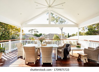 Interior photography of a residential timber deck in a coastal style home with cane furniture table setting