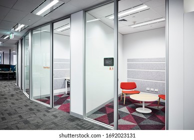 Interior Photography Of A Row Of Small Modern Corporate Office Meeting Rooms With Orange Chairs And Pink And Grey Geometric Carpet