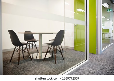 Interior Photography Of A Simple Meeting Room With A Round Table, Black Eiffel Chairs, A Lime Green Door Shot Through The Glass Office Wall On The Outside In The Hallway