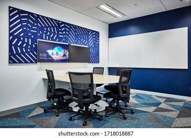 Interior Photography Of A Small Meeting Room With Wall Mounted Screens, Sound Proofing Panels And Timber Meeting Table And Chairs