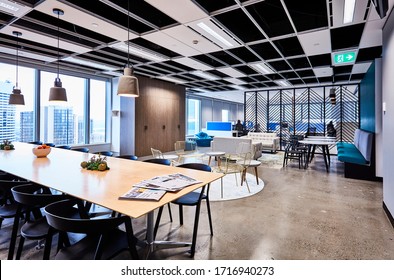 Interior Photography Of A Stylish Corporate Breakout Area With Long Lunch Table And Chairs, Meeting Areas And Lounge With City Views, An Open Plan Office In The Background
