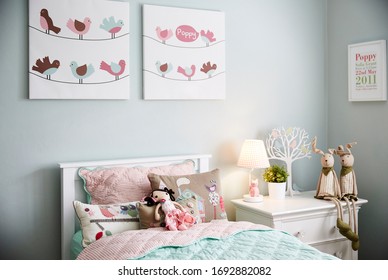 Interior Photography Of A Stylish Little Girl's Bedroom With Aqua And Pink Bedding, Decorative Cushions, Side Table With Lamp, Wall Art And Toys