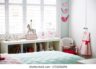 Interior Photography Of A Stylish Little Girl's Bedroom With Aqua And Pink Bedding, Decorative Cushions, Side Table With Lamp, Bookshelf, Wall Art And Toys