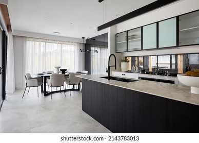 Interior Photography Of A Suburban Family Home, A Black Tap And Kitchen Sink In A Quartz Stone Bench Top Counter Top Within A Modern Kitchen, A Dining Room In The Background.