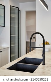 Interior Photography Of A Suburban Family Home, A Black Tap And Kitchen Sink In A Quartz Stone Bench Top Counter Top Within A Modern Kitchen, A Laundry Room In The Background.