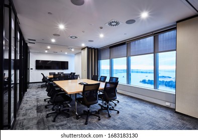 Interior photography of two large modern corporate board rooms divided by a concertina wall with neutral tones, large beech timber meeting tables, black chairs, glass walls and harbour views