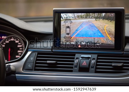 Interior of premium car with rearview camera dynamic trajectory turning lines and parking assistant steering wheel turned right. Driver assistance parking system. Help assist options of luxury car. 