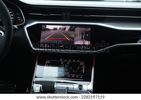 Interior of premium car with rearview camera dynamic trajectory turning lines and parking assistant steering wheel turned right. Driver assistance parking system 