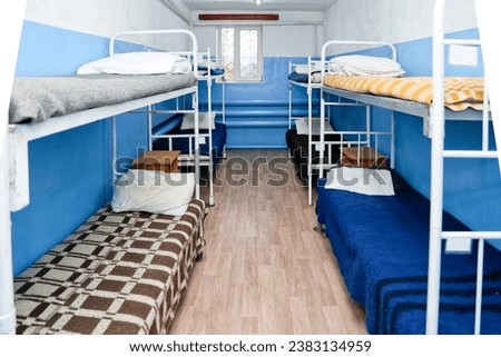 The interior of the prison room in blue with beds and bunk beds