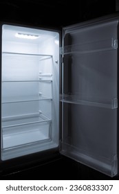 el interior del frigorífico con la puerta abierta sobre un fondo negro con luz en la parte superior del frigorífico