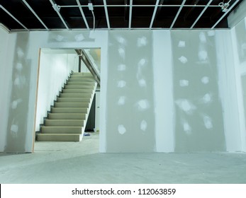 Interior Remodeling Work On An Existing Commercial Building - Ceiling Is Being Prepared For Electricity System- With Stair In The Next Room And Wall Are Prepared For Painting