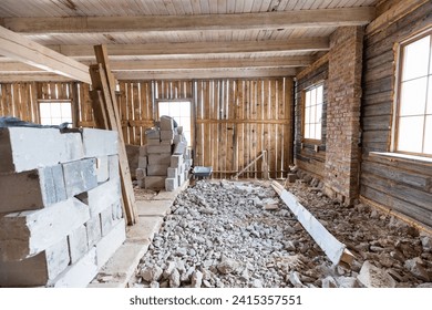 Interior renovation in progress with exposed wooden beams and pile of rubble on the floor in an old house